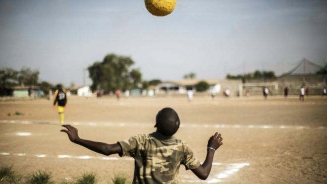 A Liberian boy plays with a ball as international Liberian football star, George Weah plays a match on a dusty pitch at the Alpha Old Timers Sports Association in Paynesville in Monrovia on April 30, 2016