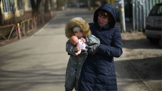 A woman carrying a child walks in east Kyiv, on February 23, 2022.