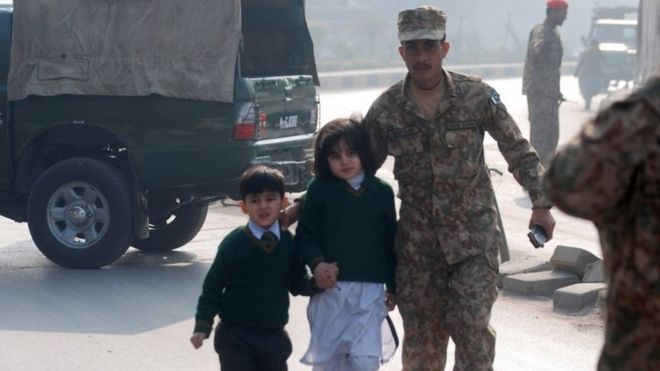Пакистанский солдат сопровождает школьников из Государственной школы армии, когда на него напали боевики Талибана в Пешаваре (16 декабря 2014 года)