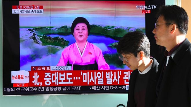 路人经过一个电视屏幕，屏幕上正在播放朝鲜洲际弹道导弹的新闻。