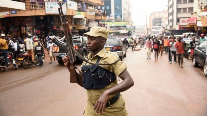 Офицер полиции Уганды поднимает его АК-47 Riffle вьсота противоположных протестующий во время демонстрации 11 июля 2018 года в Кампале, протестуя спорный налог на использовании социальной медиа
