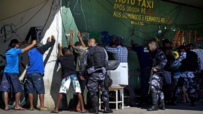 Премьер-министр милиции милиционеров обыскивает подозреваемых в трущобах Мангейра во время операции по поиску и захвату в Рио-де-Жанейро, Бразилия, 17 июля 2017 года