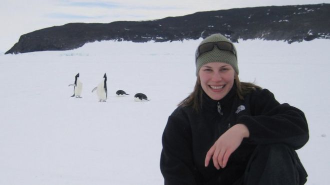 Женщина стоит на коленях на снегу перед несколькими пингвинами