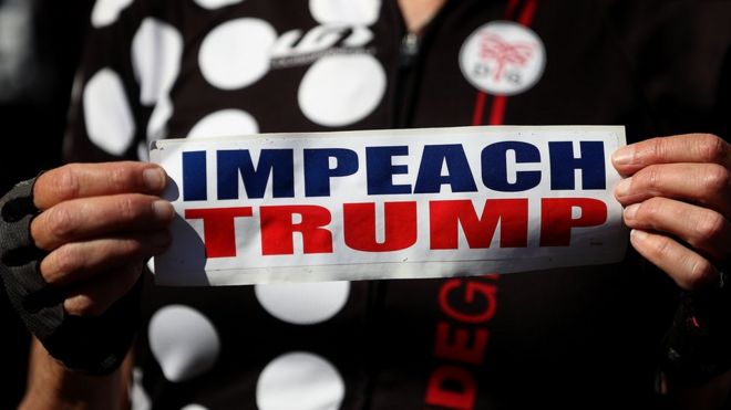 Протестующий держит табличку с призывом к импичменту президента США Дональда Трампа во время митинга и пресс-конференции в мэрии Сан-Франциско