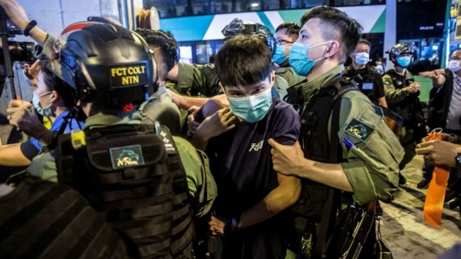 Офицер полиции по охране общественного порядка (R) задерживает мужчину (C) во время акции протеста районных советников в торговом центре в Yuen Long в Гонконге 19 июля 2020 г.