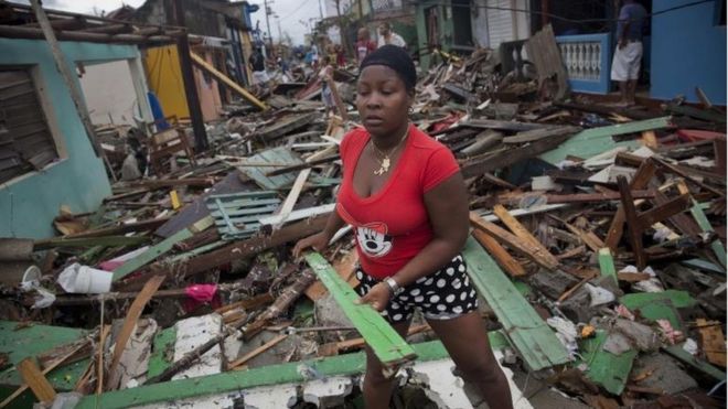 una mujer levanta escombros en Baracoa, Cuba