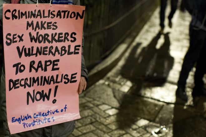 Протестующий держит плакат во время бдения при свечах, чтобы отметить международный день прекращения насилия в отношении работников секс-бизнеса, организованный английским коллективом проституток