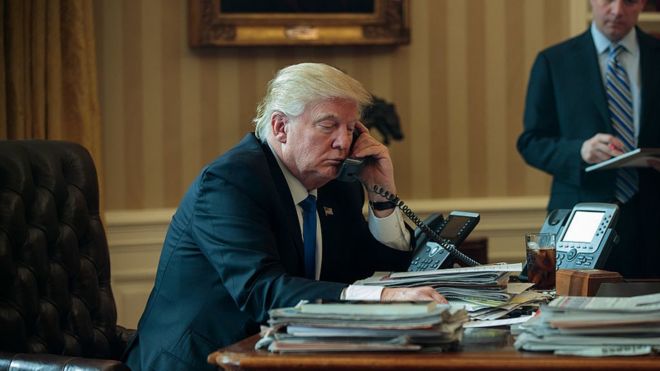 White House Chief of Staff Reince Priebus (R) looks on as President Donald Trump speaks on the phone with Russian President Vladimir Putin in the Oval Office of the White House, January 28, 2017 in Washington, DC
