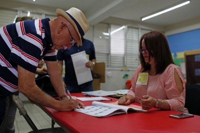 Мужчина подписывает список для голосования, прежде чем подать свой голос во время референдума о политическом статусе Пуэрто-Рико на избирательном участке в Гуайнабо 11 июня 2017 года.