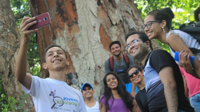 Jovens do programa Jovem Explorador, liderado pelo professor Levi Jucá, no interior do Ceará, tiram uma selfie do grupo em frente a uma árvore
