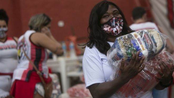Mulher recebe alimentos doados em favela no Rio