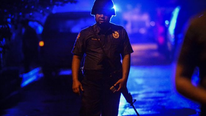 Полицейский стоит на страже у места происшествия, когда неизвестный мужчина убил мужчину в городе Кесон, Метро Манила, Филиппины
