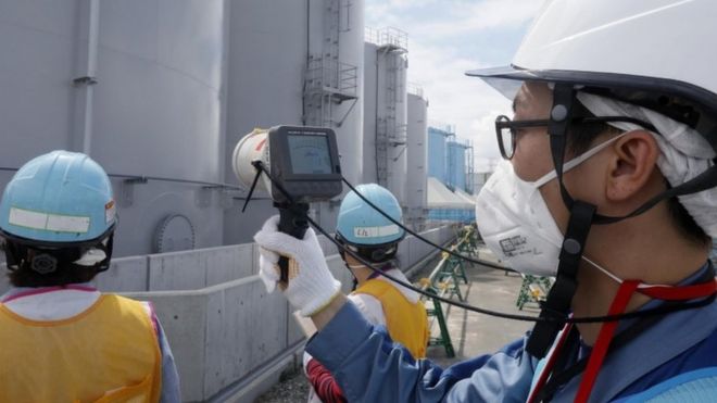 A staff member of the Tokyo Electric Power Company measures radiation levels at the Fukushima nuclear power plant