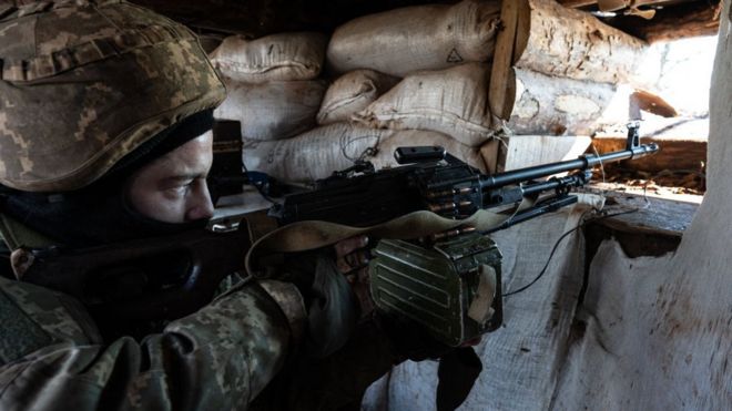 Un militar ucraniano apunta con una ametralladora a través de una abertura en un búnker de sacos de arena durante ejercicios militares.
