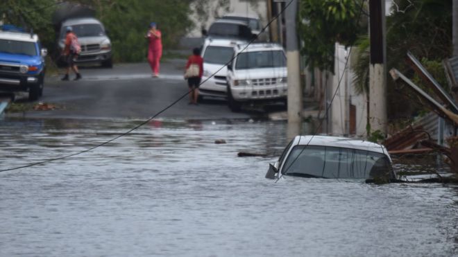 A car is viewed stuck in a flooded street in the San Juan neighbourhood of Santurce.