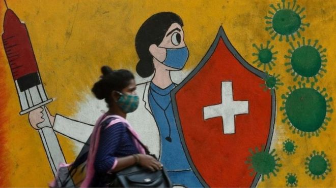A woman walks past a graffiti on a street, amidst the spread of the coronavirus disease (COVID-19) in Mumbai, India, May 10, 2021.