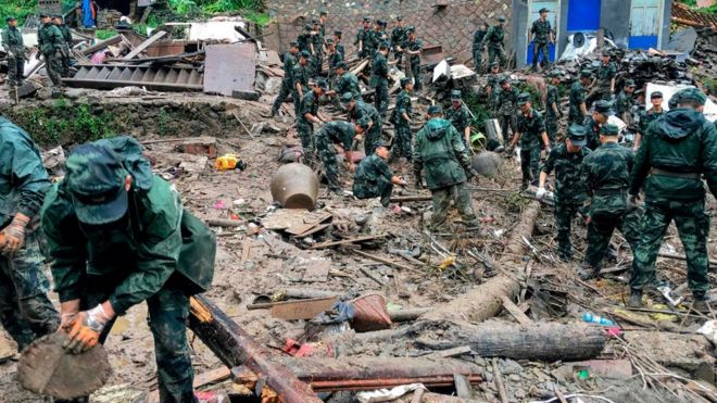 Tim penyelamat mencari korban selamat di puing-puing bangunan yang rusak akibat tanah longsor yang dipicu badai di provinsi Zhejiang, China.