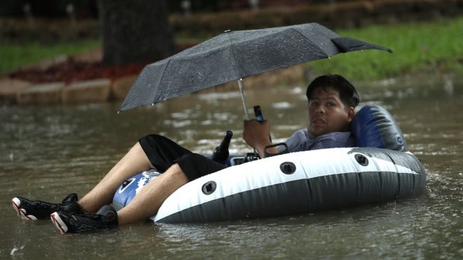A man sits on an inflatable boat in flood waters in Houston.