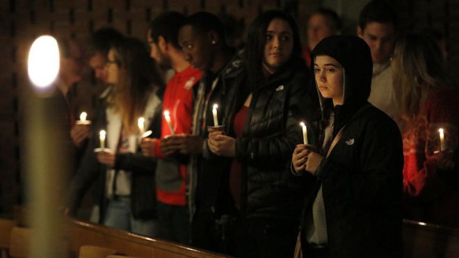 Гости на мгновение стоят после того, как зажигают свечи во время бдения в епископальной церкви Святого Стефана в Колумбусе, штат Огайо