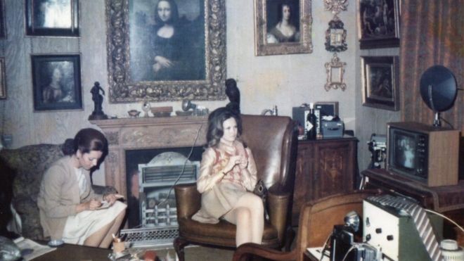 Dos mujeres sentadas debajo de una pintura de Mona Lisa colgando sobre la chimenea de un departamento de Londres de 1960.