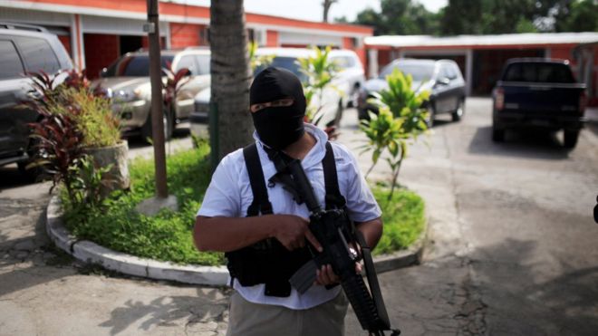 Полицейский стоит на страже возле мотеля, захваченного во время рейда в Сальвадоре