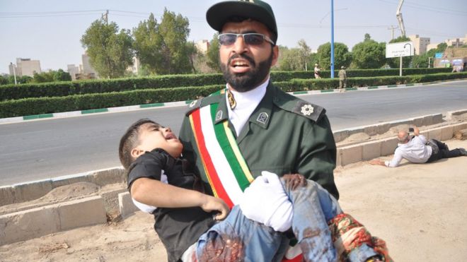 Солдат несет раненого ребенка на месте нападения