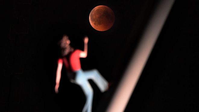 Затмение «кровавой луны» изображено со скульптурой американского художника Джонатана Борофски «Женщина, идущая в небо» 27 июля 2018 года в Страсбурге, восточная Франция.