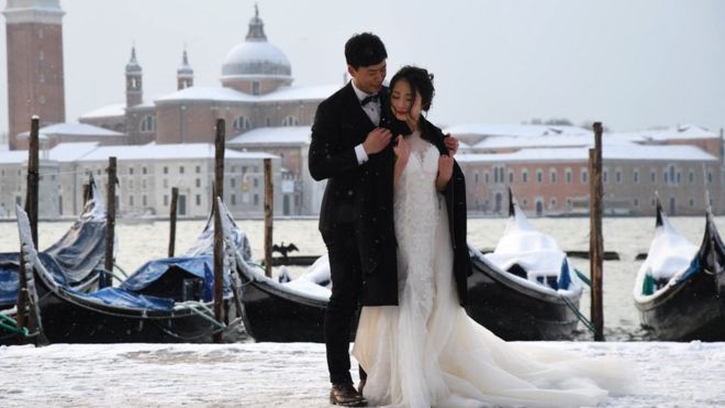 زوجان يلتقطان صور زفاف في ميدان القديس مرقس بمدينة البندقية في إيطاليا في أعقاب هطول الثلوج خلال الليل.