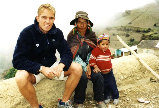 Саймон Томас с одним из детей поможет марки в Перу