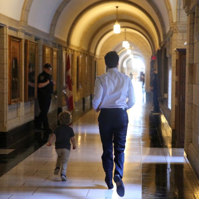 Сфотографированный сзади Джастин Трюдо и его трехлетний сын бегут по дорогому правительственному зданию, а улыбающиеся охранники смотрят на