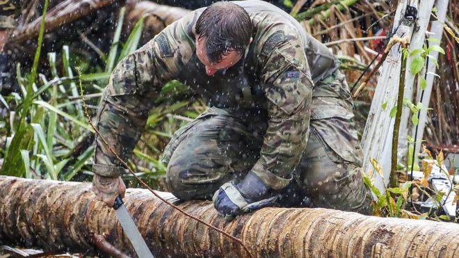 Мужчина в военной одежде распиливает упавшую ветку