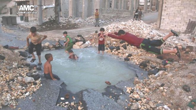 Un cráter sirve de estanque para los niños en Alepo