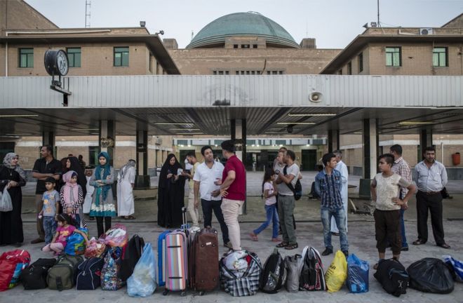 Pasajeros hacen fila con sus maletas en la estación