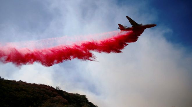 Самолет сбрасывает огнезащитный состав, когда пожарные сражаются с пожаром Вулси, который продолжает гореть в Малибу, Калифорния, США, 11 ноября 2018 года