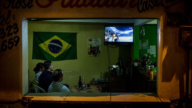 Люди смотрят Олимпиаду по телевизору в баре Рио