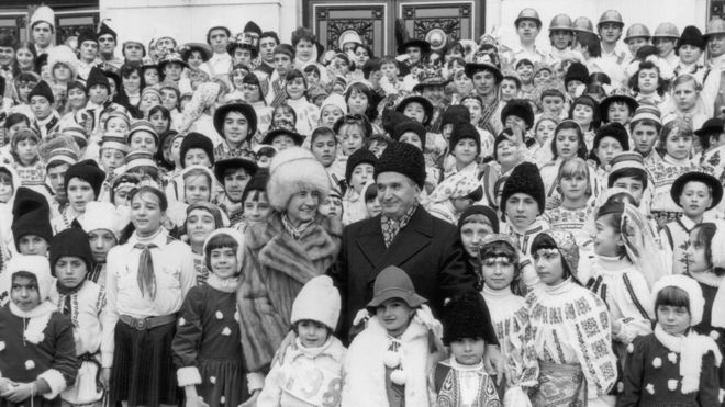 Коммунистический лидер Румынии Николае Чаушеску изображен в 1985 году вместе с женой Еленой и большой группой детей в национальных костюмах.
