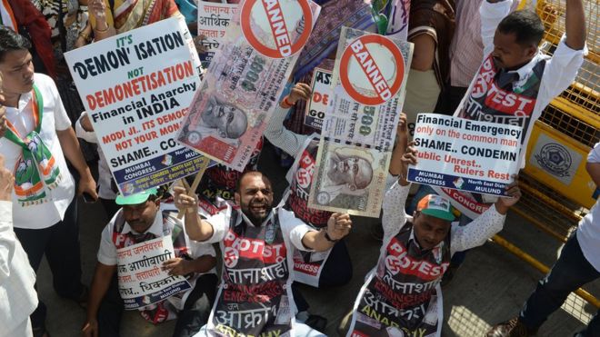 Индийский протестующий держит плакаты с запрещенными купюрами в 500 и 1000 рупий во время акции протеста против демонетизации в Мумбаи 28 ноября 2016 года.