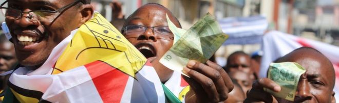 Протестующие держат старые банкноты Зимбабве в Хараре, Зимбабве - среда, 3 августа 2016 года
