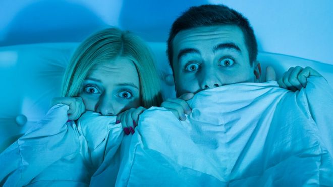 Una pareja aterrada viendo una película