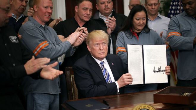 Президент Трамп, держа подписанный меморандум о введении тарифов на сталь и алюминий