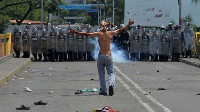 Một người biểu tình đứng trước vệ binh quốc gia Venezuela ở Cucuta, Colombia