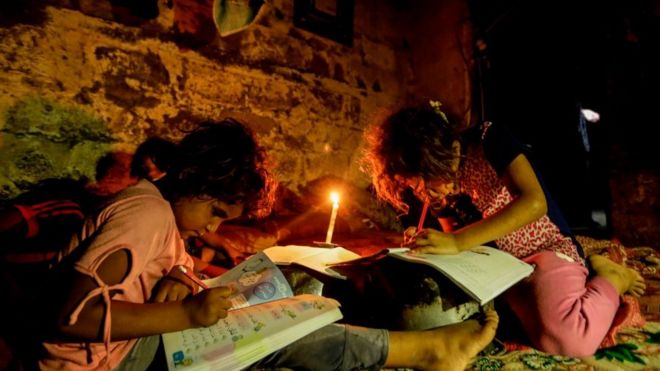 Palestinian children do homeowrk by candlelight September 2017