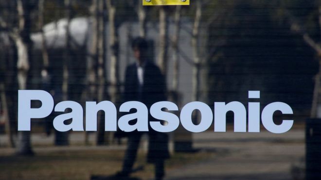 Человек отражается на логотипе Panasonic в Panasonic Centre в Токио