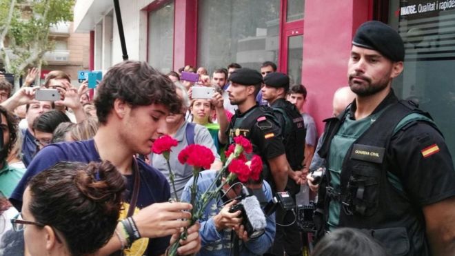 Pro-independence offer flowers to Spanish police outside a newspaper office in Valls, Catalonia, 9 September