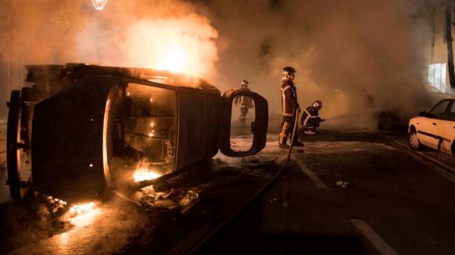 Firefighters work to put out a fire near a burning car in Nantes, France. Photo: 4 July 2018