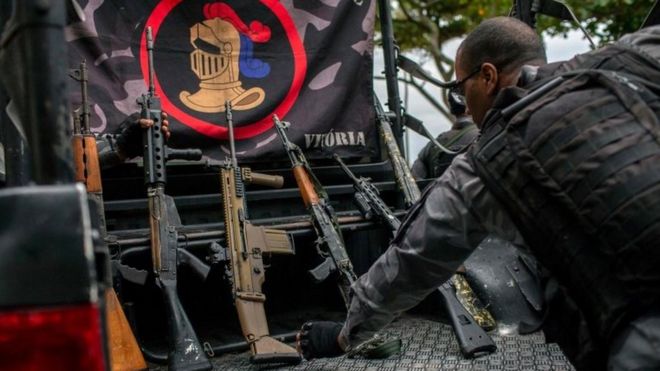 Сотрудник военной полиции показывает оружие, изъятое во время полицейской операции, в ходе которой они преследовали торговцев наркотиками, убегавших из фавелы Вавилония, до того, как их поймали после перестрелки на пляже Вермелья в районе Урка в Рио-де-Жанейро, Бразилия, 8 июня 2018 года.