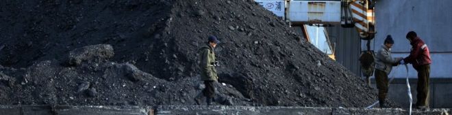 Северокорейские рабочие работают на берегу реки Ялу в северокорейском городе Синуидзу 8 февраля 2013 года, который находится недалеко от китайского города Даньдун. Груды угля видны.