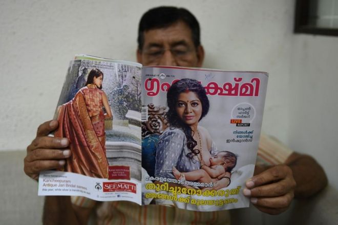 На этой фотографии, сделанной 2 августа 2018 года, в Нью-Дели мужчина читает журнал, в котором актриса из Кералы Гилу Джозеф кормит грудью ребенка.