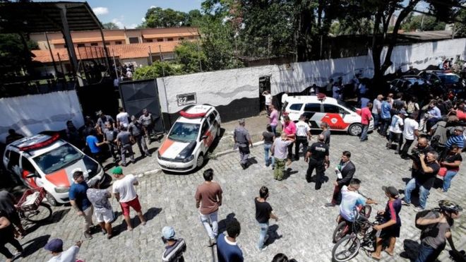 Полиция стоит на страже в школе после стрельбы, когда люди собираются, в столичном регионе Сан-Паулу, Бразилия, 13 марта 2019 года