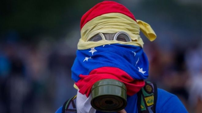 Протестующий в противогазе замечен во время столкновений с Венесуэльской Национальной Гвардией (ГНБ) в Каракасе, Венесуэла, 10 апреля 2017 года.
